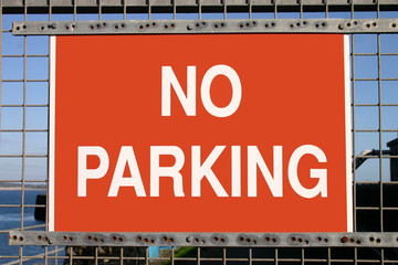 red no parking sign on a metal gate.