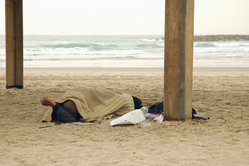 homeless person sleeping on beach