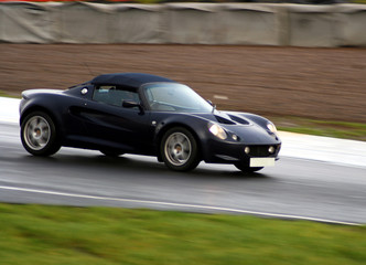Obraz na płótnie Canvas dark blue sports car on wet racing circuit