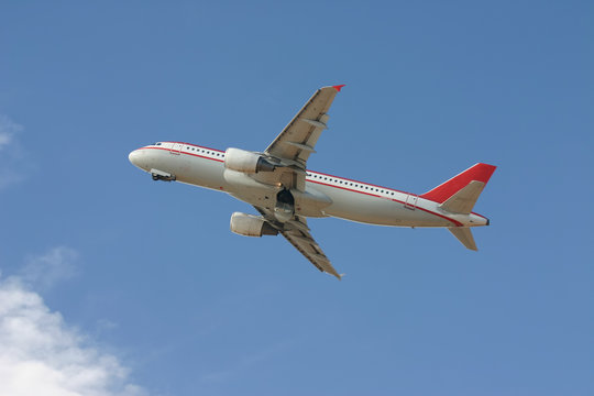 red and white commercial aircraft taking off