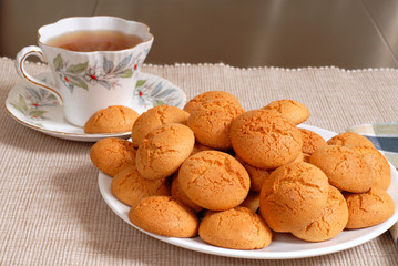 plate of crisp italian amaretti cookies with a cup of hot tea in