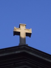 stone cross on church against blue sky