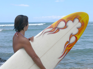 young woman with surfboard watching the waves