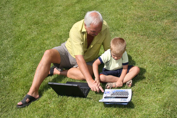 grandfather and grandson working on laptops - 1909367
