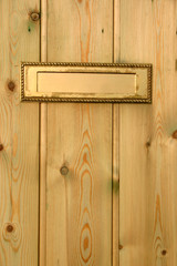 a gold color letterbox in a wooden door.