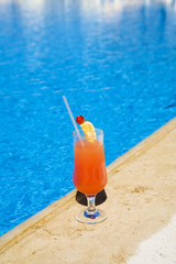 cocktail stands on edge of pool.