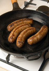 sausages in a black frying pan on gas stove