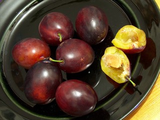 fresh, nutritious, ripe plums on a black plate