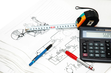 design drawings, calculator, pens and measuring ta