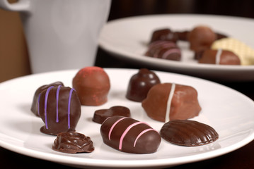 close up of two plates of chocolates with a cup of hot chocolate