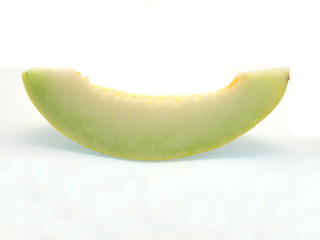 eine Scheibe frische hellgrüne entkernte Honigmelone freigestellt auf weißem Hintergrund
