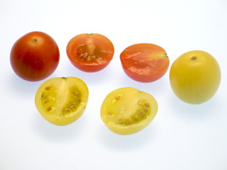 frische rote und gelbe Kirschtomaten, ganze und halbe Stücke freigestellt auf weißem Hintergrund