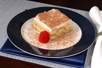 tiramisu with sliced strawberry on a blue plate