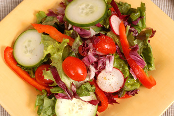 an overhead view of a crisp healthy salad on a yellow plate