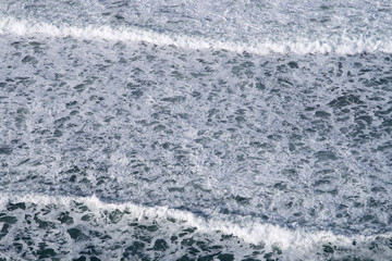 Fototapeta na wymiar aerial view of white sea surf breaking on the shor