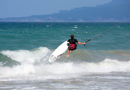 young male kitesurfer jumping on the sea
