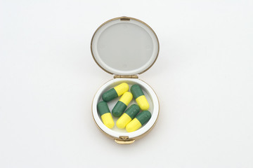 green & yellow pills in a pillbox