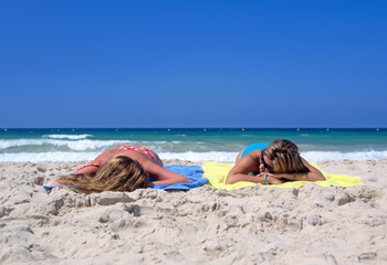 Fototapeta na wymiar two sexy young girls laying on a sunny beach on va