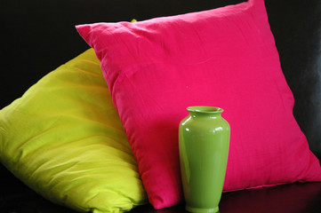 Still life with two cushions and one vase in red and green colors and black background.
