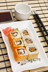 sushi (rolls) on a plate, chopsticks, wasabi, sake