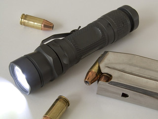 Tactical flashlight that is on with high capacity magazines and ammunition for a semi-automatic pistol © Guy Sagi