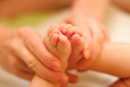 mother gently hold baby leg in hand