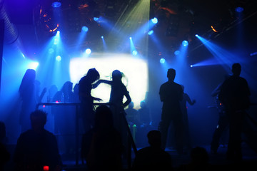 Obraz na płótnie Canvas Dancing ludzi w niebieskich świateł dyskotekowych