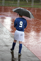 the spare player in football is hidden from a rain under a umbre