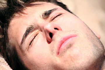 jeune homme a la plage ébloui au soleil