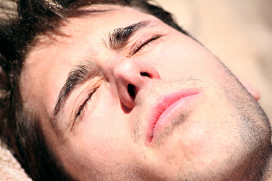 jeune homme a la plage &eacute;bloui au soleil