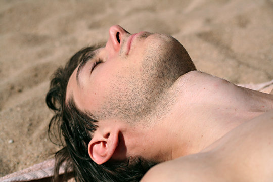 jeune homme a la plage bronzant au soleil