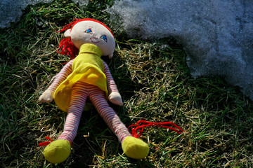 rothaarige Puppe im Gras und Schnee