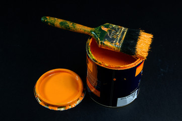 can of yellow paint with brush