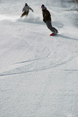 two snowboarders carving