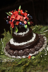 a fancy chocolate wedding cake with red flowers