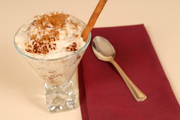 glass of rice pudding with cinnamon with a maroon napkin