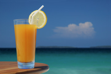 glass of mango juice with straw and lemon twist.