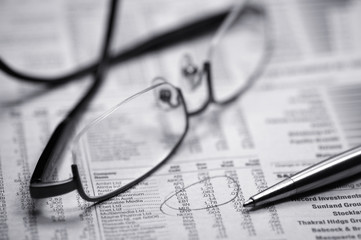 glasses on a newspaper with a pen
