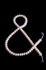 pink pearl's bead as a & sign isolated on black