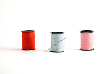 3 sewing thread spools and a needle.