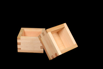 two wooden sake cups on a black background