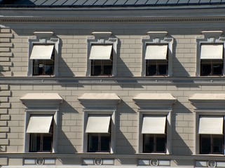 graue fassade mit heruntergelassenen markisen