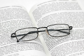 Fototapeta premium reading glasses with light frame over the open book
