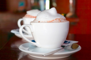 two cappuccino cups with milk foam and cinnamon