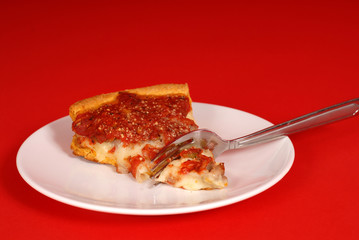 a piece of deep dish pizza on a white plate, red background
