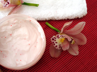 container of cosmetic moisturizing cream with pink orchids with