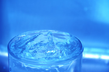 closeup of drop of water splashing in glass
