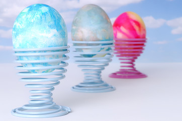three decorated easter eggs against a blue sky with clouds