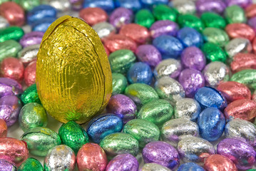 one big yellow easter egg amongst pile of small co