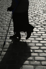 old woman silhouette crossing a cobbled street